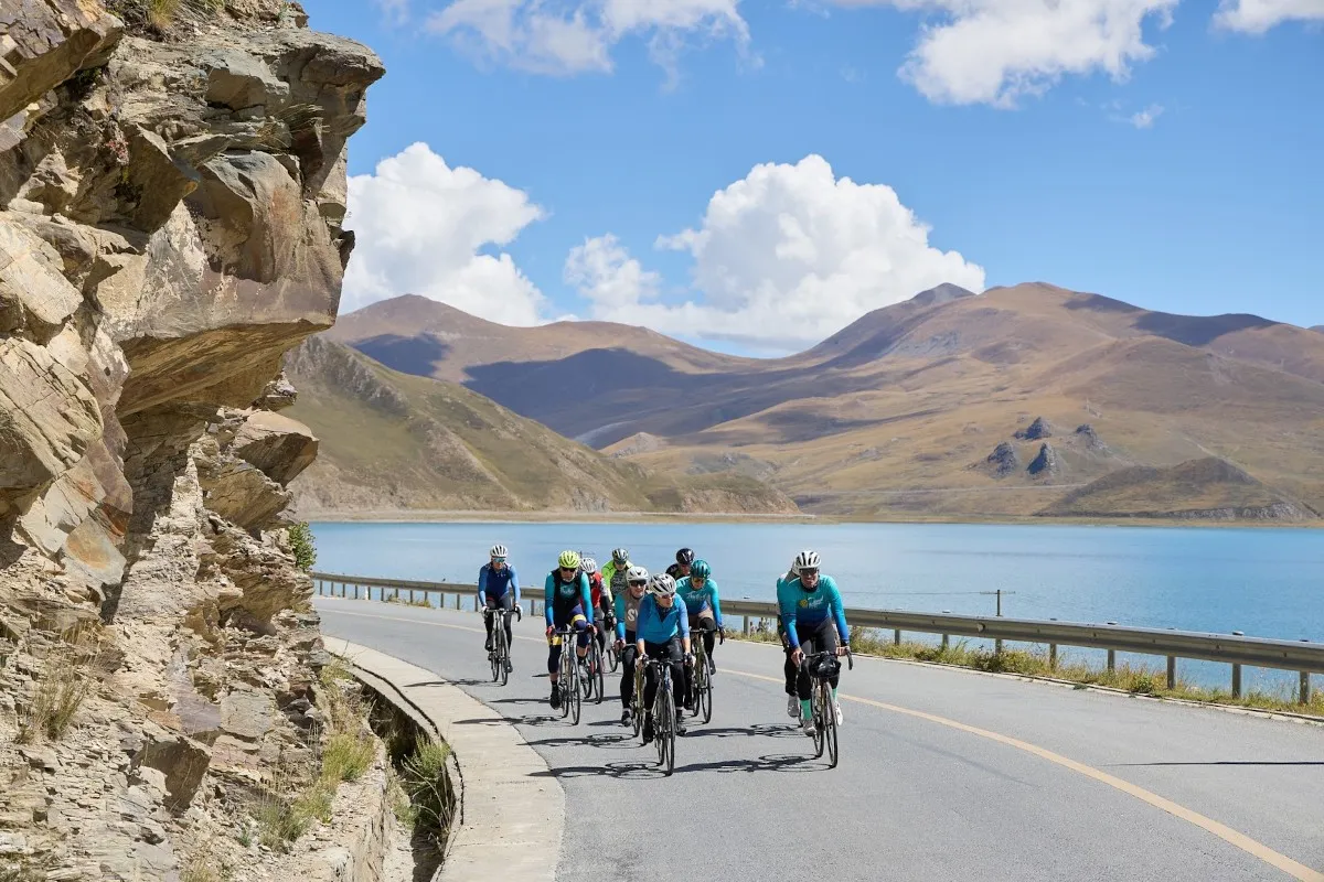 Cyclists riding past a lake in the mountains